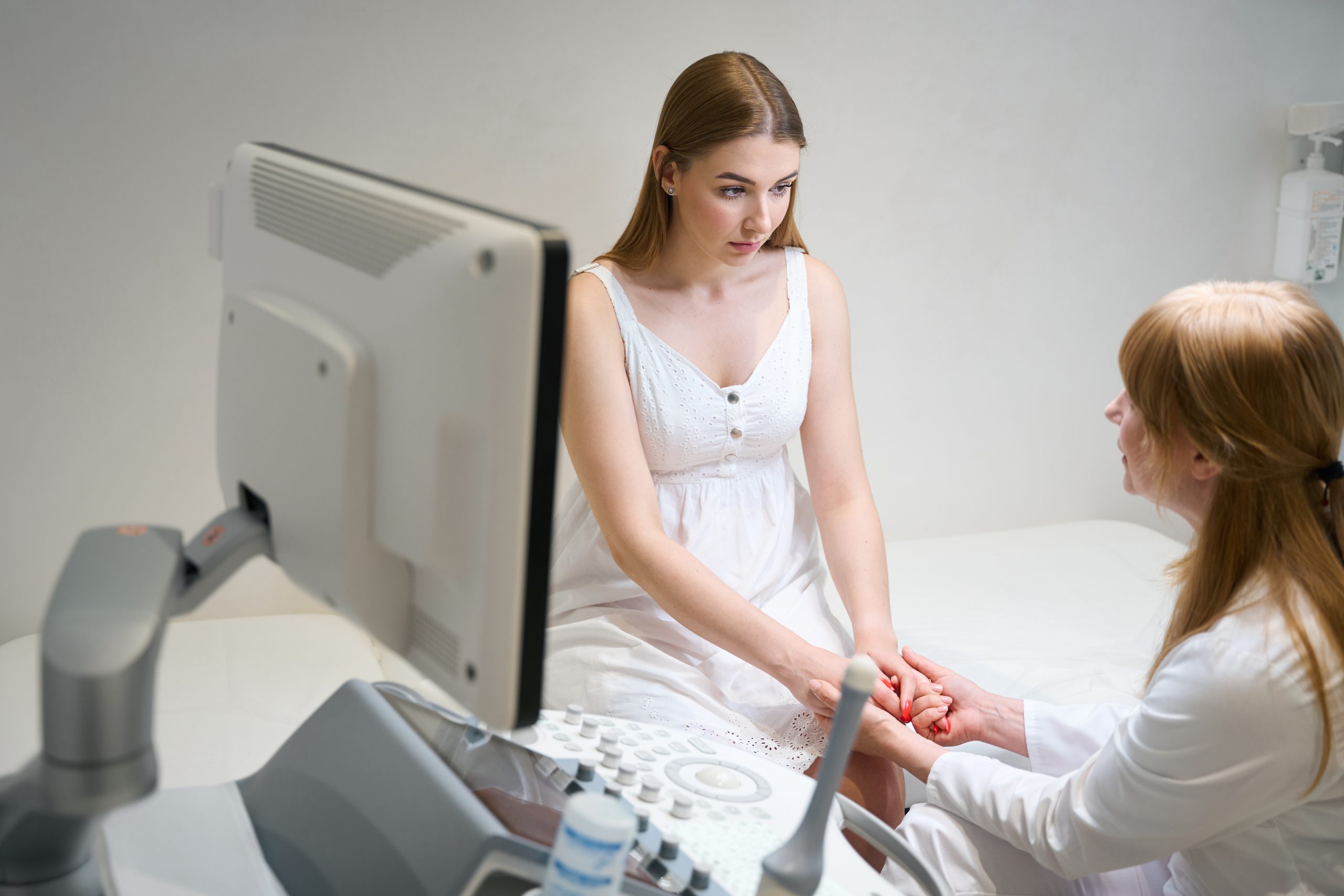 Female medic warmly communicates with young woman in ultrasound room